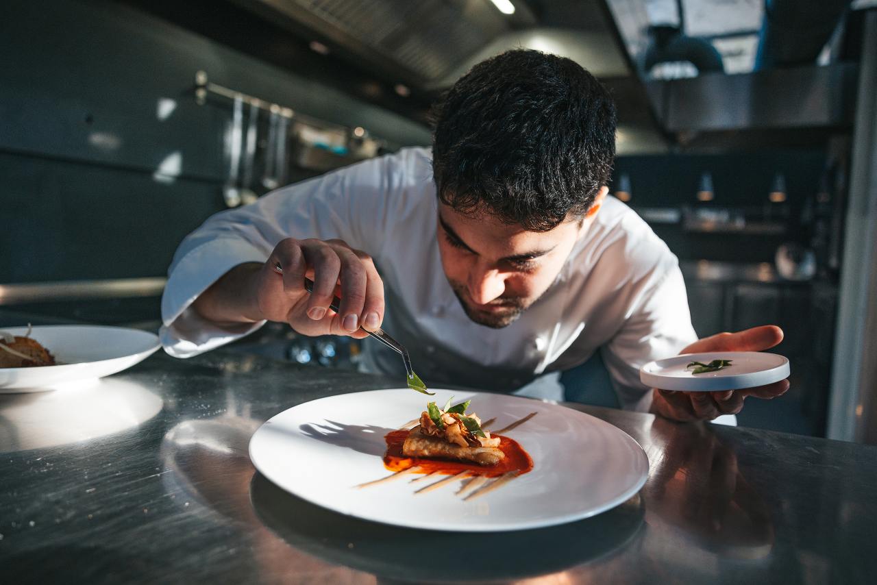 Chef preparing a gilthead bream dish in a luxury restaurant, close up view.